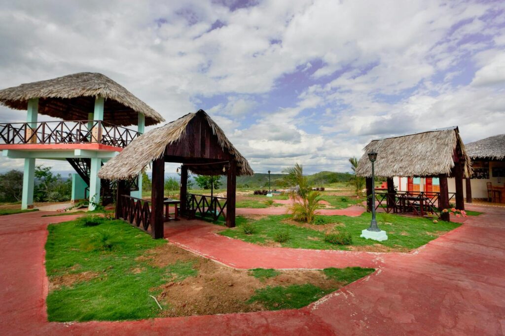 Scenic park featuring traditional thatched roof gazebos under a cloudy sky.