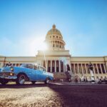 blue and white volkswagen beetle parked near white concrete building during daytime