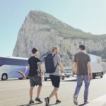 three men walking on street near vehicles during daytime