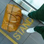 person stranding beside brown leather handbag
